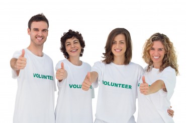 Cheerful group of volunteers giving thums up on white background